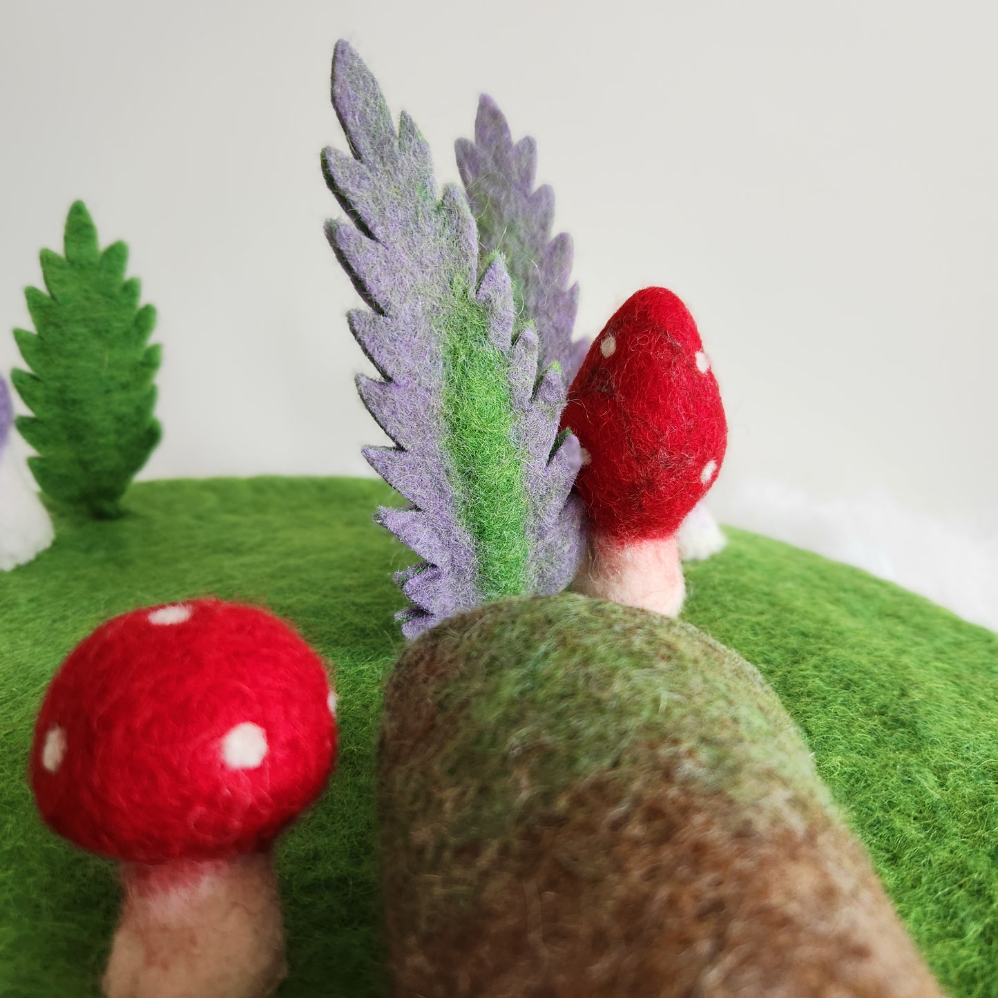FOREST FLOOR STORYTELLING PLAYMAT - GREEN FELT PLAYMAT WITH ATTACHED MUSHROOMS, FERNS AND A HOLLOW LOG.