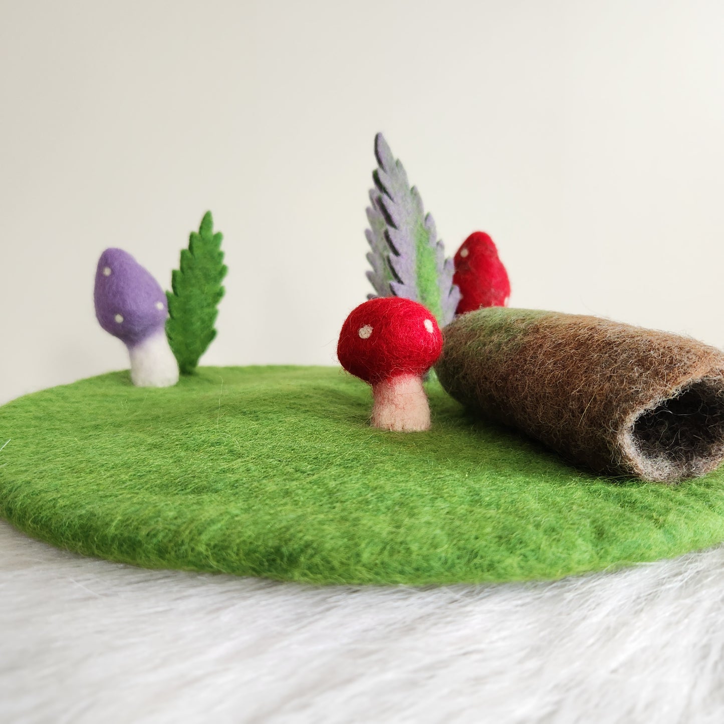 FOREST FLOOR STORYTELLING PLAYMAT - GREEN FELT PLAYMAT WITH ATTACHED MUSHROOMS, FERNS AND A HOLLOW LOG.