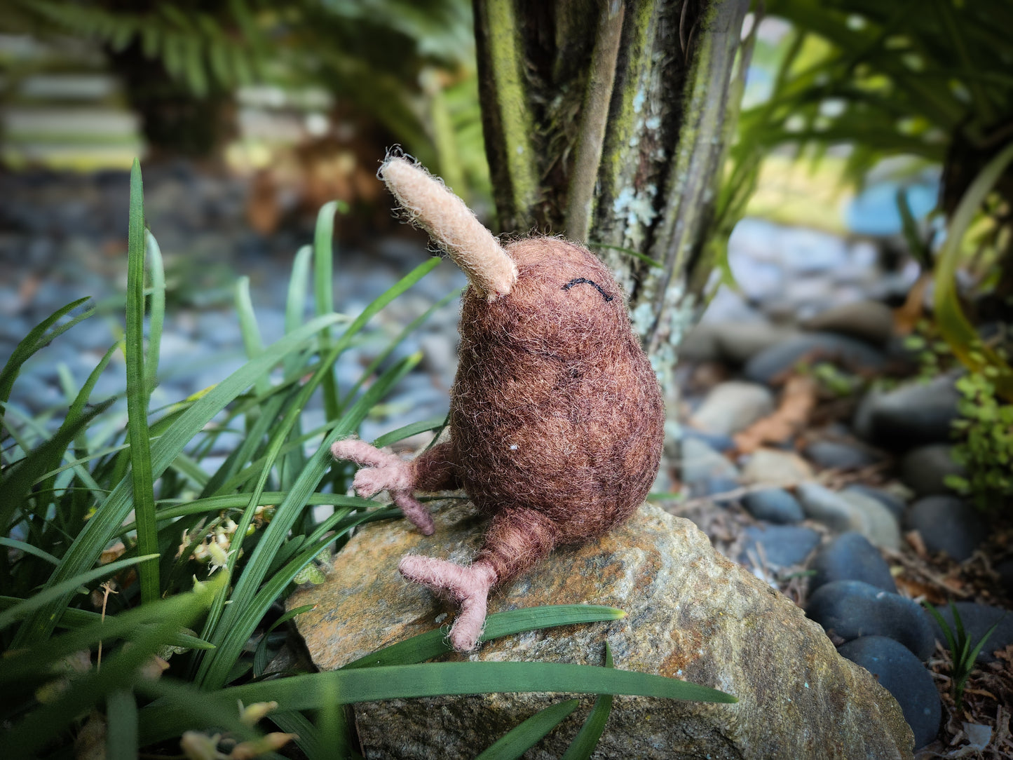 Felt Baby Kiwi Toy sitting on rock in bush