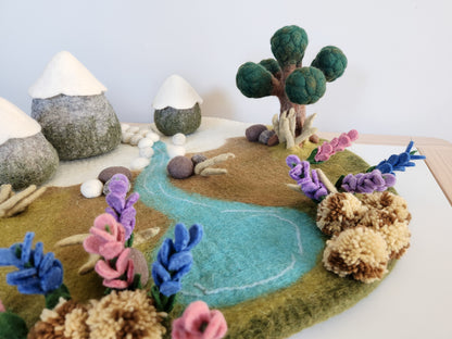 Handmade felt landscape with tree, flowers, and a river on a white background