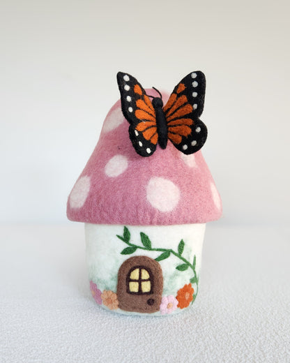 Felt mushroom house with a butterfly on a white background
